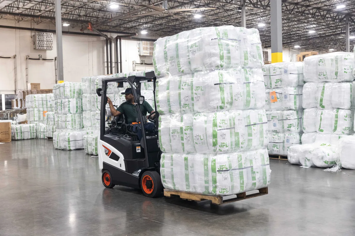 Operator working a counterbalance truck in a warehouse aisle