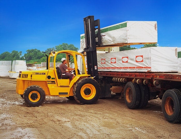 Sellick S80 rough-terrain forklift unloading lumber from a flatbed