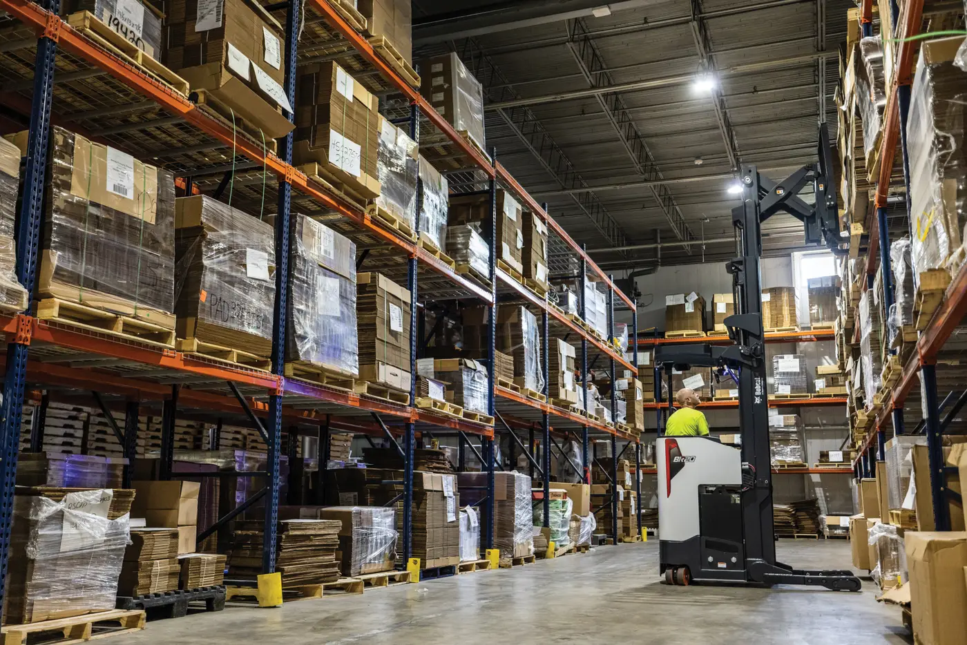 Reach truck working a narrow aisle between loaded racking