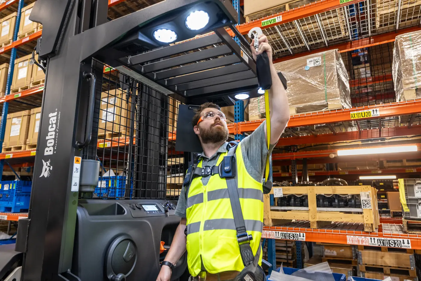 Technician recording a scheduled inspection beside a forklift in a warehouse aisle