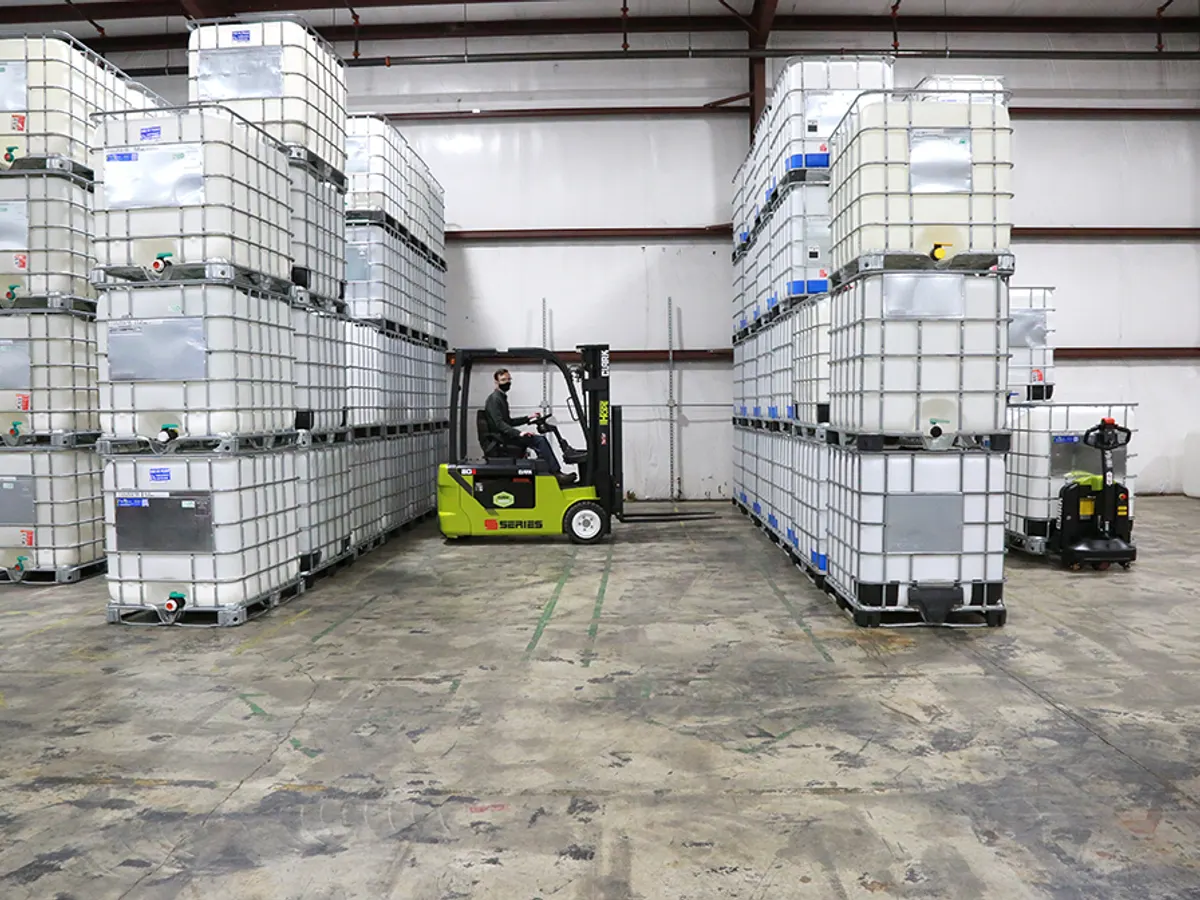 Clark electric forklift working between tall stacks of tote containers in a warehouse