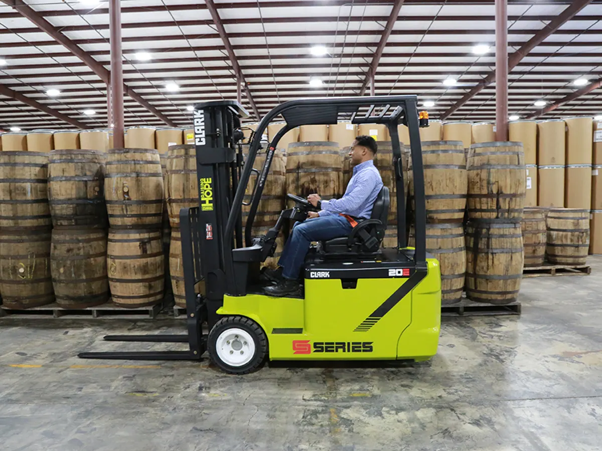 Clark electric forklift in front of stacked barrels in a warehouse